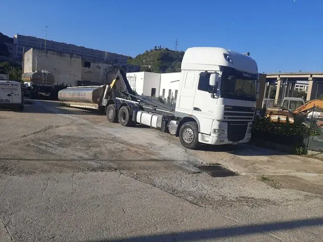 Il camion scarrabile DAF bianco di Center Clean con il rimorchio cisterna nel piazzale, cielo sereno